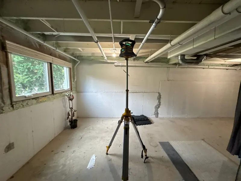 Before: a finished basement with water at the base of the wall, then a new interior drain along it