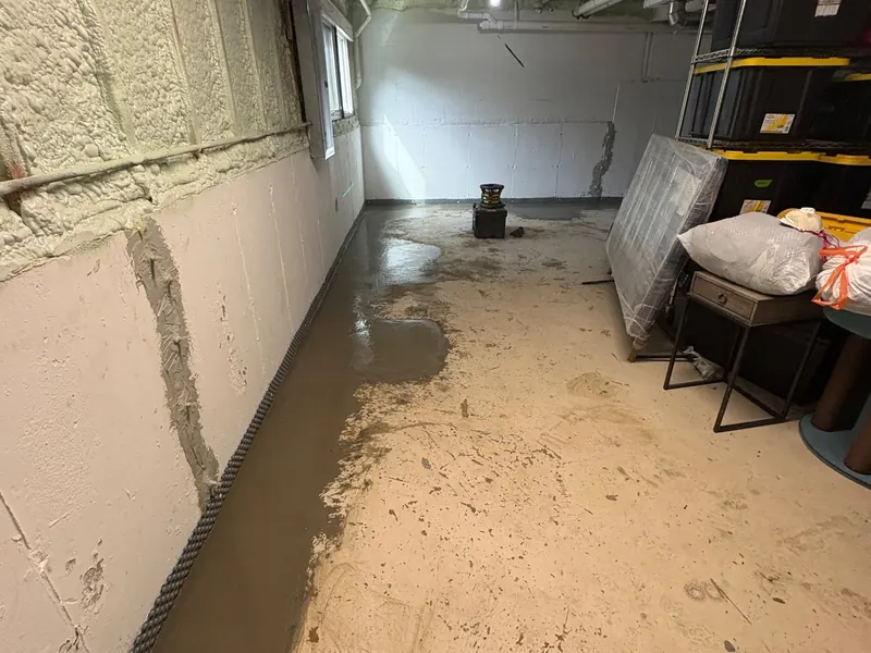 The same basement wall and grey patch, with a dark new strip along the floor at its base.