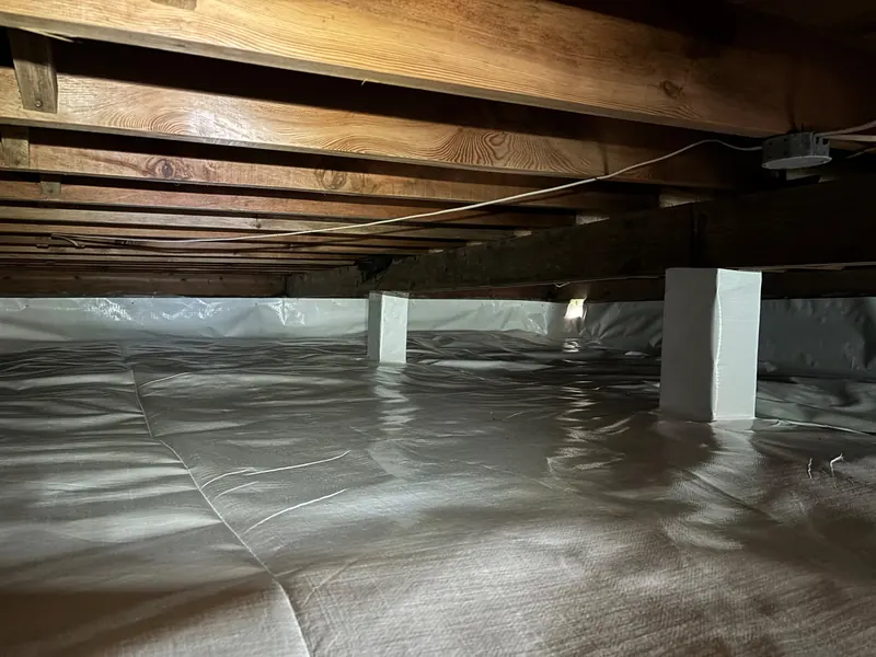 After: a crawl space with torn plastic on the dirt floor, then a sealed white liner across the floor and walls